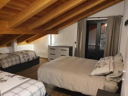 two beds in a room with wooden ceilings at Casa Vacanza Lo Nânò in Fenis