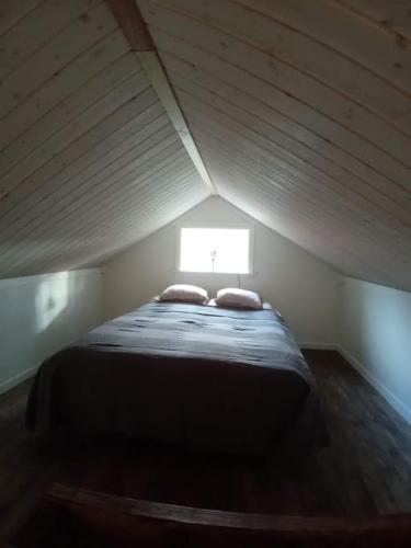 uma cama num pequeno quarto com uma janela em Nyrenoverad charmig gäststuga med sovloft i Järpen em Järpen