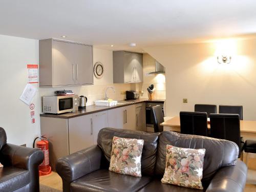 a living room with a couch and a kitchen at Courtyard Cottage in Smailholm