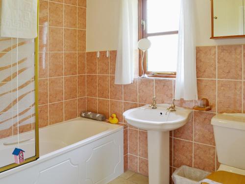 a bathroom with a tub and a sink and a toilet at Birchwood in Marhamchurch