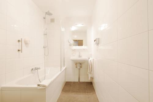 a bathroom with a tub, sink, and mirror at Hotel Dordrecht in Dordrecht