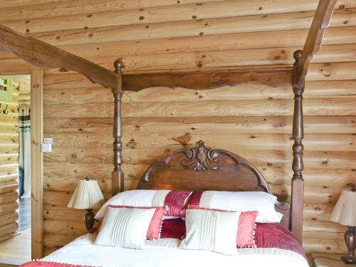 Cama en habitación con pared de madera en Ashknowe Log Cabin - S4590 en Glenfarg