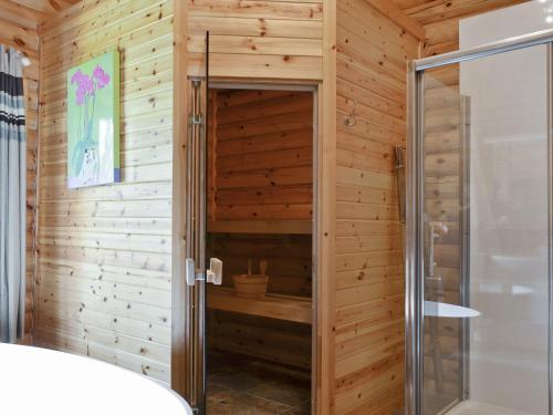 uma casa de banho com um chuveiro numa parede de madeira em Ashknowe Log Cabin - S4590 em Glenfarg