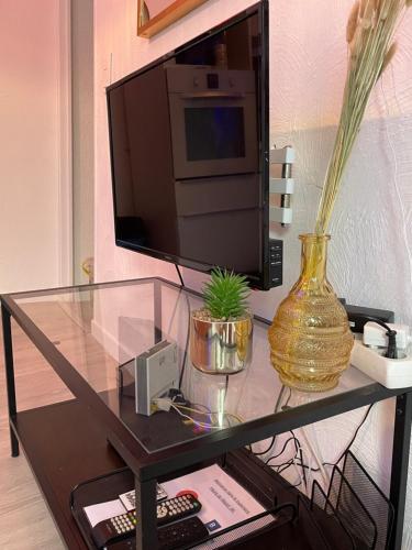 a glass table with a television and a vase on it at La garde Studio atypique Le Rocher, climatisation, belle décoration in La Garde