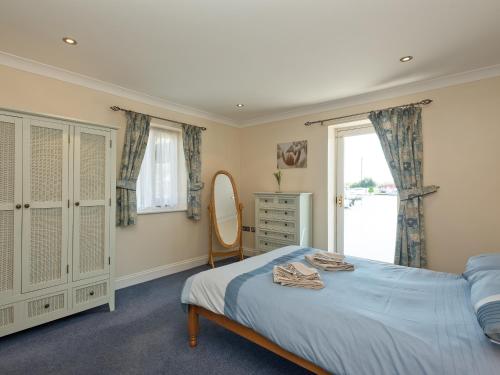 a bedroom with a bed and a mirror and a window at Puddle Inn Duck in Horning
