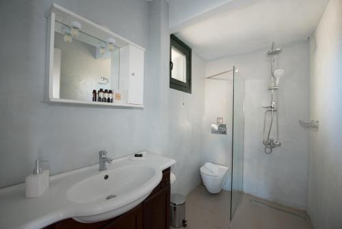 uma casa de banho branca com um lavatório e um chuveiro em Villa Endless Blue em Kalamitsi