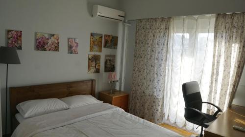 1 dormitorio con 1 cama, 1 silla y 1 ventana en Όμορφο διαμέρισμα ρετιρέ 5ου ορόφου, στου Zografou, en Atenas