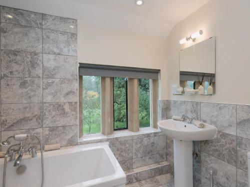 uma casa de banho com uma banheira, um lavatório e um espelho. em Hall Cottage em Brampton