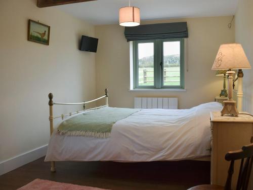a bedroom with a bed and a window at Wagtail Cottage in Foxton