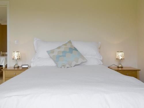 a white bed with a pillow on top of it at Bramley Cottage in Brean