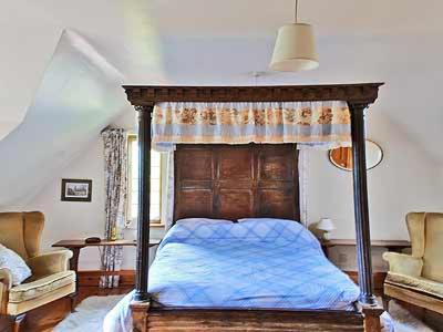 a bedroom with a canopy bed with a blue blanket at Netherall Manor Lodge in Soham