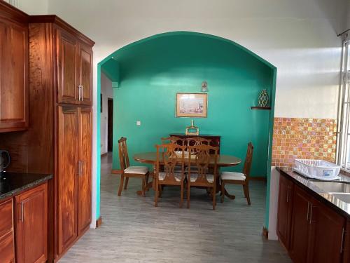 a kitchen with a table and a green wall at Travellers Villa in Roseau