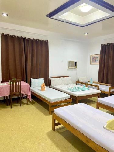 a room with three beds and tables and chairs at Angela's Pool Resort in Puerto Princesa City