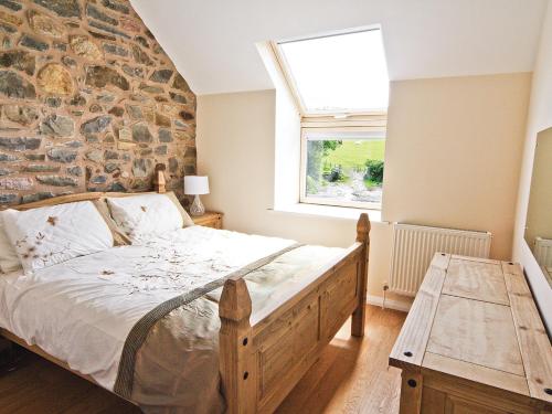 a bedroom with a bed and a stone wall at Smithy Barn - Hw7592 in Bettws-yn-Rhôs