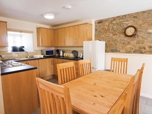 a kitchen with a wooden table and a white refrigerator at Smithy Barn - Hw7592 in Bettws-yn-Rhôs