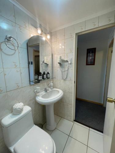 a white bathroom with a toilet and a sink at Hospedaje Baquedano in Puerto Natales