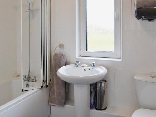 a white bathroom with a sink and a window at Sea Breeze in Amble