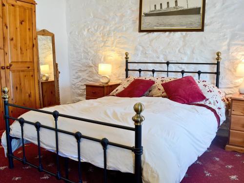 a bedroom with a large bed with red pillows at Porth Cormon Farmhouse in Llangwnadl