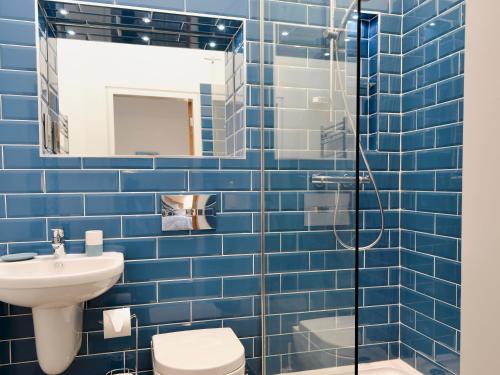 a blue tiled bathroom with a toilet and a sink at Bluebell Barn in Dunnington