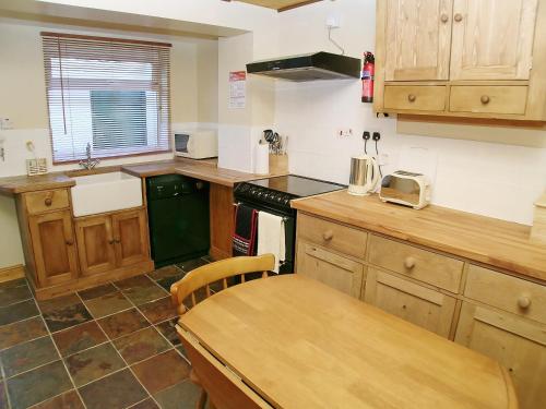 a kitchen with wooden cabinets and a wooden table at Lobster Cottage in Flamborough