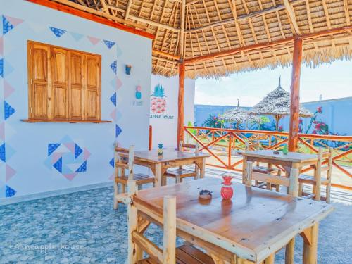 restauracja z drewnianymi stołami i widokiem na ocean w obiekcie Pineapple House w mieście Nungwi