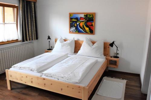 Schlafzimmer mit einem Holzbett mit weißer Bettwäsche und Kissen in der Unterkunft Ferienhaus Durstberger in Ehrwald