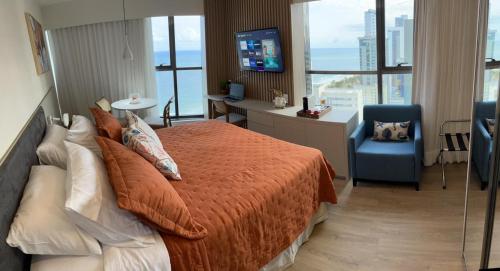 um quarto com uma cama, uma secretária e uma televisão em Flat Beira Mar Boa Viagem- Beach Class Internacional em Recife