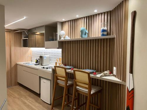 a kitchen with a bar with chairs and a counter at Flat Beira Mar Boa Viagem- Beach Class Internacional in Recife