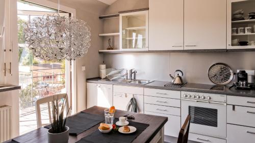 uma cozinha com armários brancos, uma mesa e um lavatório em Charmante, großzügige Ferienwohnung Villa Fleurie em Bretten