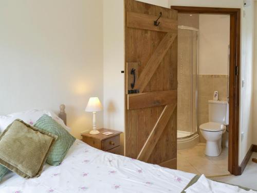 PoundstockにあるCider Barnのベッドルーム1室(ベッド1台付)、納屋のスライドドアが備わります。