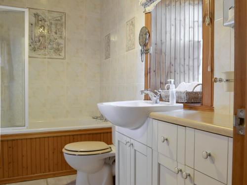 a bathroom with a sink and a toilet and a tub at Hazels Cottage in Kilchenzie