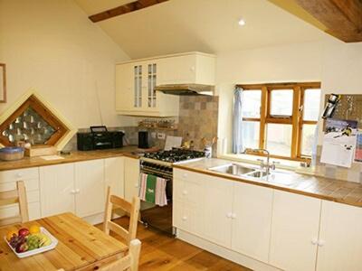a kitchen with white cabinets and a sink and a table at The Barn in Gringley on the Hill