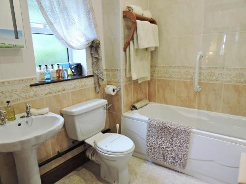 a bathroom with a toilet and a sink and a tub at Moorlands Cottage in Levisham