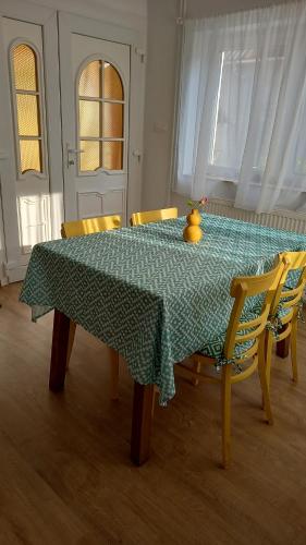 a dining room table with a green tablecloth and yellow chairs at Kuckó Apartman in Badacsonytördemic