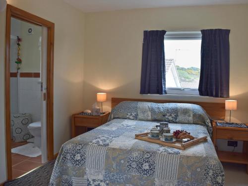 a bedroom with a bed with a tray of food on it at Bracelet Cottage in The Mumbles