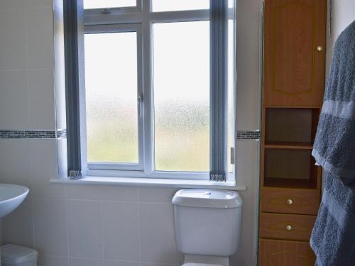 a bathroom with a toilet and a window at Shell Seekers Cottage in Hornsea