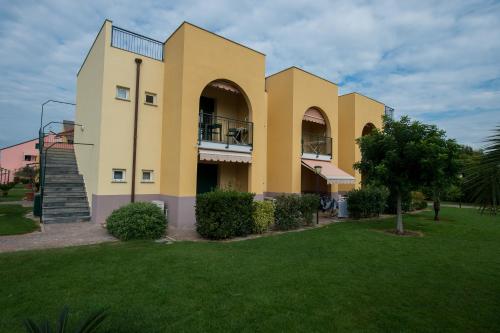 a large yellow building with a grass yard at Residence Borgomare in Albenga