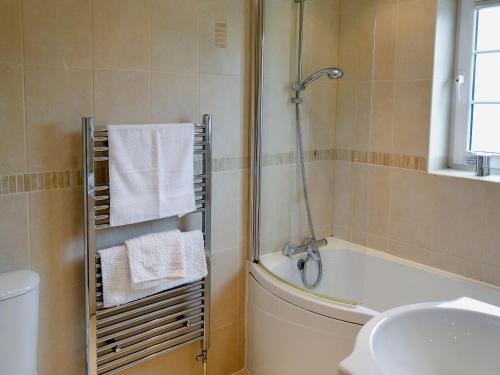 a bathroom with a shower and a tub and a sink at The Old Butchers in Crantock