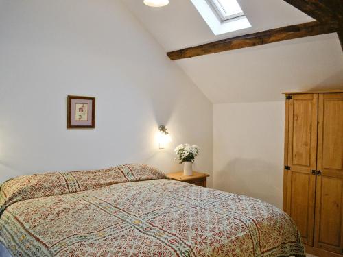 a bedroom with a bed and a wooden cabinet at The Grooms Cottage in Ashperton