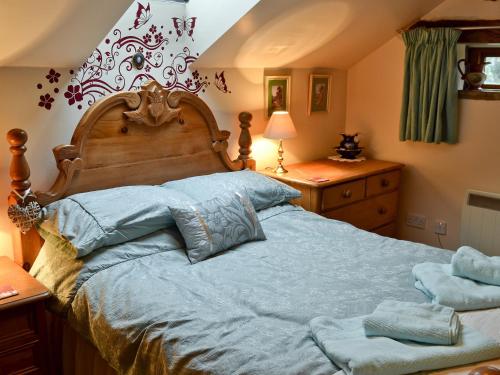 a bedroom with a large bed with blue sheets at Marl Farm Cottage in Hayfield
