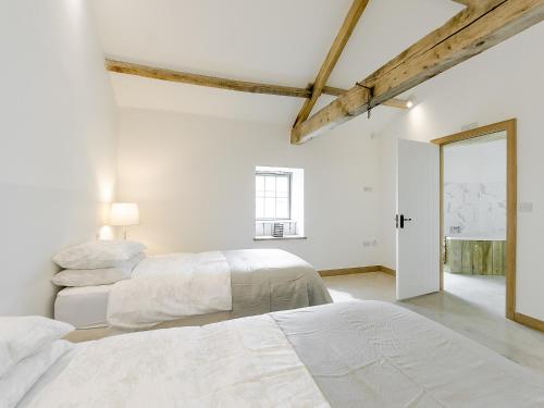 2 łóżka w pokoju z białymi ścianami i drewnianymi belkami stropowymi w obiekcie Clawdd Y Parc w mieście Llangibby