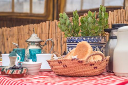 a table with a basket of bread and cups on it at Riad Dari in Tetouan
