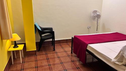 a room with a bed and two chairs and a fan at Muffys Guest House in Arpora