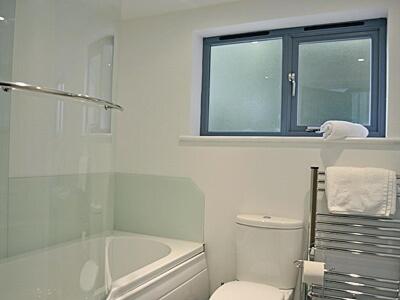 a white bathroom with a toilet and a window at Grove Lodge - 27847 in Marazion