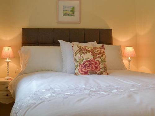 1 cama con sábanas y almohadas blancas y 2 lámparas en Honeysuckle Cottage - Uk4177 en Mayfield