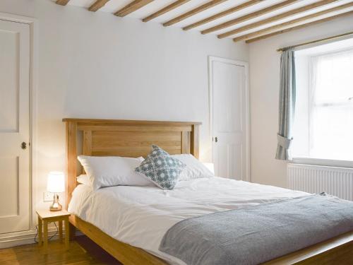 1 dormitorio con cama blanca y cabecero de madera en The Plough en Bampton