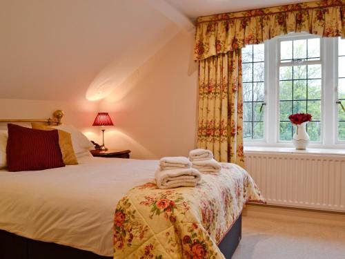 a bedroom with a bed and a window with towels at Old School House in Wyck Rissington