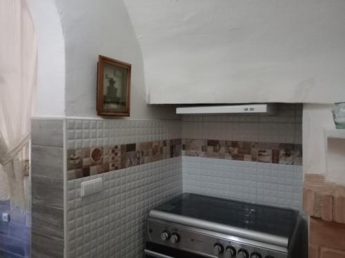 Il dispose d'une cuisine avec une cuisinière et un mur en carrelage. dans l'établissement CASA RURAL CORTIJO con piscina MOLINO EL TARAHAL, à El Tarahal