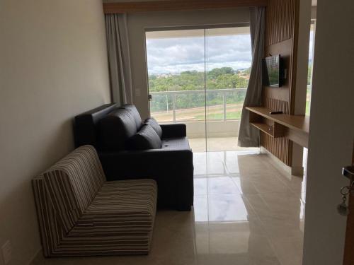a living room with a couch and a large window at Condomínio Recanto do Bosque - RBF-10 in Caldas Novas