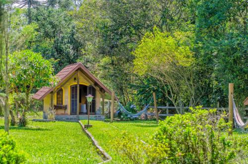 a small house with a hammock in a yard at Pousada - Casa de Barro in Santo Antônio do Pinhal